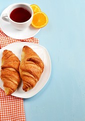 Croissants, tea and orange juice for breakfast. Copyspace above