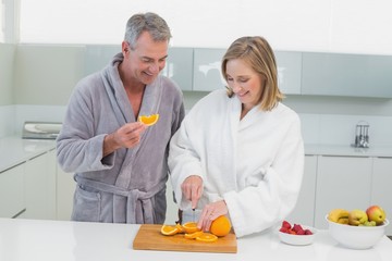 Happy couple cutting orange in kitchen