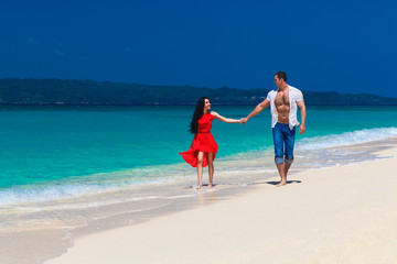 young loving couple walk through the tropical beach
