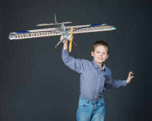 Happy boy playing with a wooden plane model