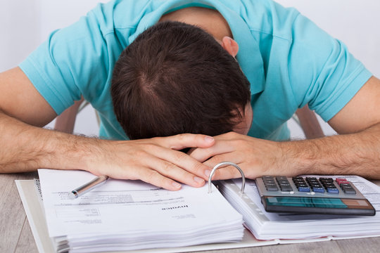 Tired Man With Bills And Calculator At Desk