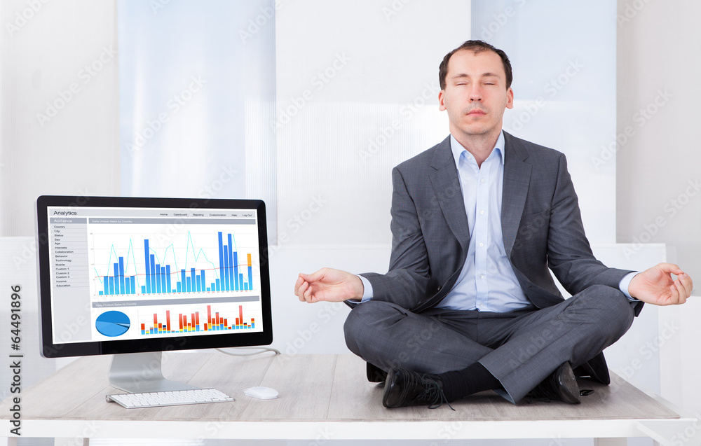Poster businessman mediating by computer on desk