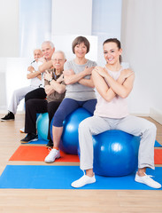 Obraz premium Trainer And Senior Customers Sitting On Fitness Balls