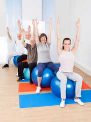 Fototapeta na wymiar Trainer And Senior Customers Stretching On Fitness Balls