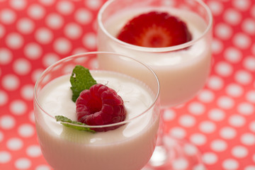 Raspberry dessert with yogurt in a glass and dotted table