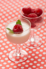Raspberry dessert with yogurt in a glass and dotted table