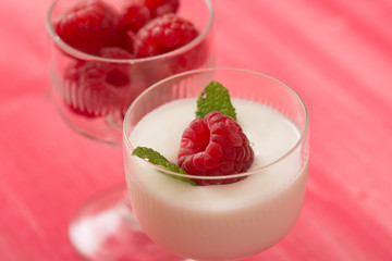 Raspberry dessert with yogurt in a glass and pink table