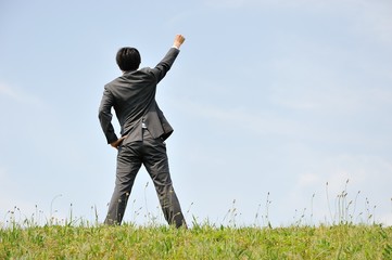 空に向かって立っているスーツの男性ビジネスマン
