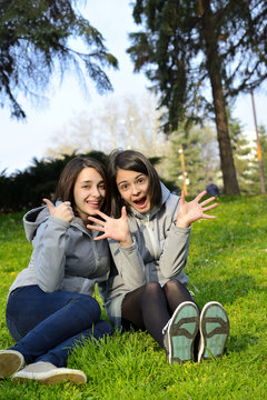 Two young woman expressing agreement and excitement in a park