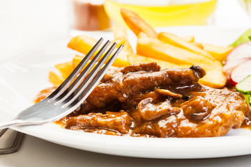 Pork chop with sauce, mushrooms and chips