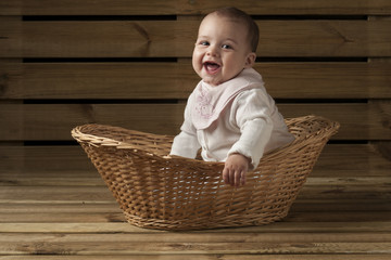 bebe recien nacido riendo dentro de una cesta fondo de madera