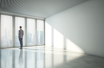 Fototapeta premium Businessman looking at city through window