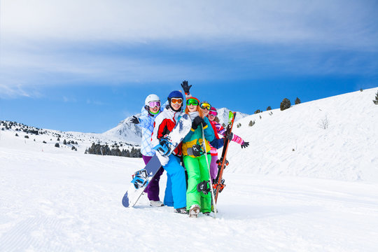 Five friends together with snowboards and skis