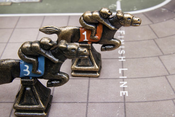 Horse race game pieces on race track.
