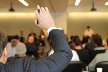 Businessman raising hand during business conference