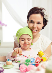 Obraz na płótnie Canvas Cute little girl painting Eater eggs with her mommy