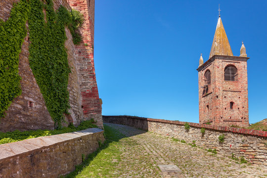 Paved walkway between brick wall and bell tower.