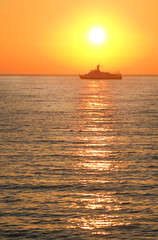 Naklejka na ściany i meble Cargo ship against colorful sunset