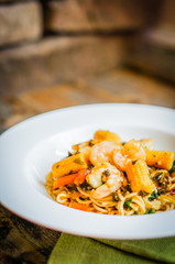 Italian pasta with shrimps and vegetables on wooden background