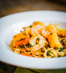 Italian pasta with shrimps and vegetables on wooden background