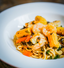 Italian pasta with shrimps and vegetables on wooden background