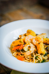 Italian pasta with shrimps and vegetables on wooden background