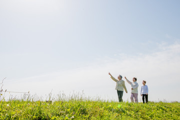 青空の日に草原の丘を散歩している3人の高齢者女性