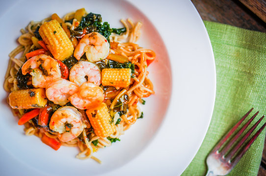 Italian pasta with shrimps and vegetables on wooden background