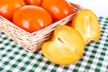 Ripe persimmons in wicker basket on table close-up