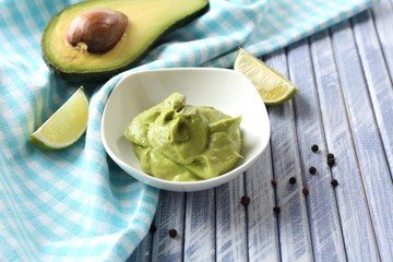 Fresh guacamole in bowl on wooden table