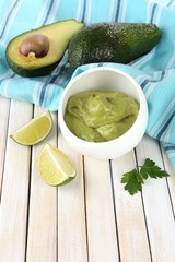 Fresh guacamole in bowl on wooden table