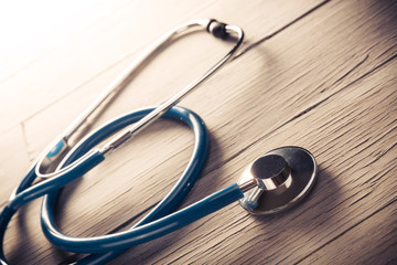 Medical stethoscope dramatically lit on a wooden table