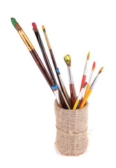 Brushes with paints in vase isolated on white