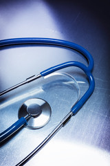 Medical stethoscope dramatically lit on a metallic table