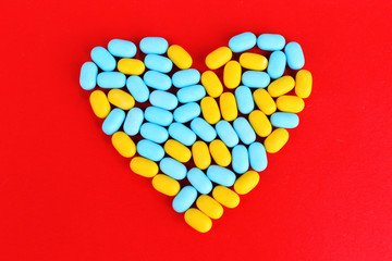 Heart of pills on red background