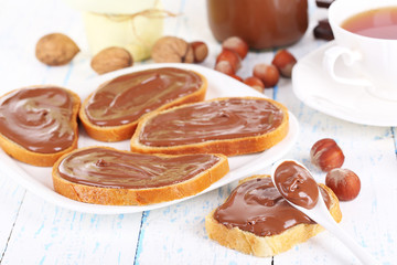 Bread with sweet chocolate hazelnut spread on plate on table