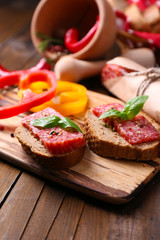 Fototapeta na wymiar Composition with knife, tasty sandwiches with salami sausage,