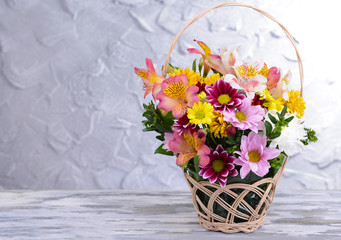 Beautiful bouquet of bright flowers in wicker basket