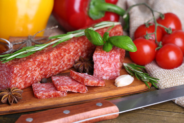 Tasty salami sausage and spices on wooden background