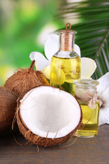 Coconuts and coconut oil on wooden table, on nature background