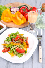 Beef salad on plate with vegetables and spices on wooden table