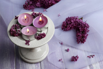 Obraz na płótnie Canvas Beautiful candles and lilac flowers on wooden table