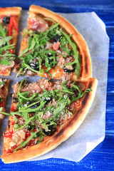 Pizza with arugula on color wooden background
