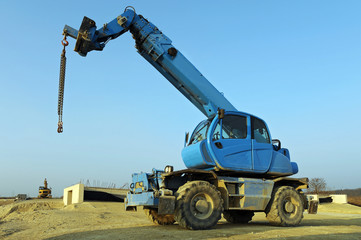 Blauer Kran mit R&auml;dern auf Baustelle