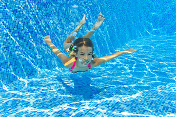 Happy active underwater girl swims in pool and having fun