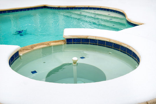 Outdoor hot tub or spa by swimming pool in snow