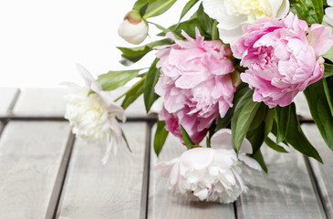Stunning peonies in white wicker basket on rustic wooden table