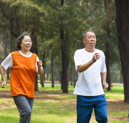 happy senior couple jogging together in the park