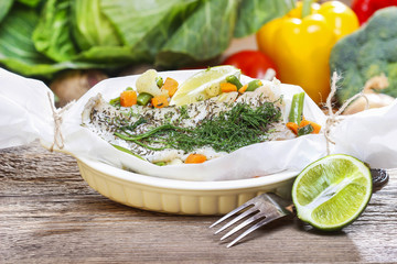 Fish in baking paper. Fresh vegetables in the background