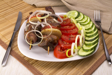 Kebab with vegetables on a plate fork knife